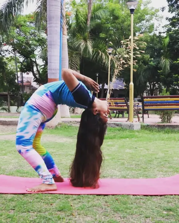 A deep backbend in Chakrasana (Wheel Pose) with my long hair touching the ground. This pose is a powerful heart opener and requires flexibility through the entire front of the body and spine.