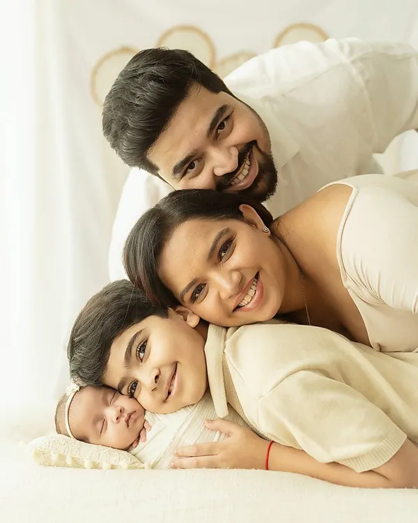 A beautiful family portrait capturing four people in one loving embrace. This light and airy style, with its neutral tones and soft focus, highlights the emotional connection and joy of the moment.