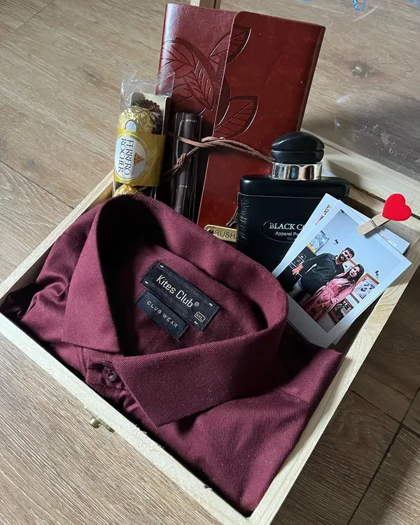 A classic and sophisticated custom hamper for him. This wooden box contains a stylish maroon shirt, a personalized journal, a premium pen, perfume, and a polaroid photo to capture a special moment.