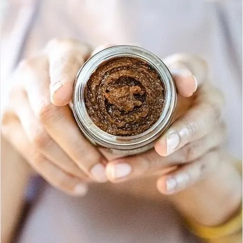 Holding a jar of my 'Gulal' sugar and oats body polisher. This exfoliating scrub is gentle yet effective, helping to remove dead skin cells and reveal a healthy glow.