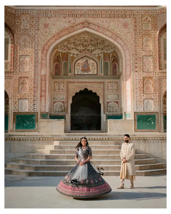 A stunning wide shot of Amandip in her twirling lehenga against the grand facade of Amer Fort. We love using the scale of Jaipur's architecture to make our couples' pre-wedding photos look truly epic.