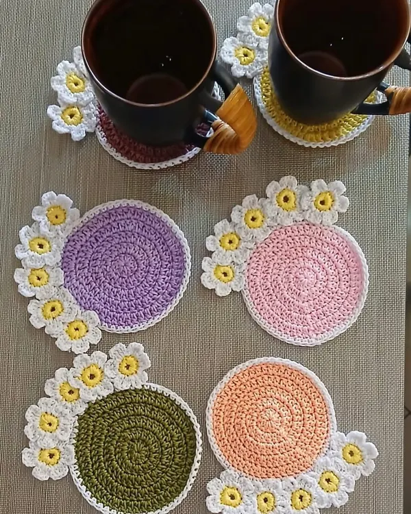 A set of my popular daisy coasters in various pastel colors. Each coaster has a solid center with a border of cheerful white and yellow flowers, perfect for a tea party.