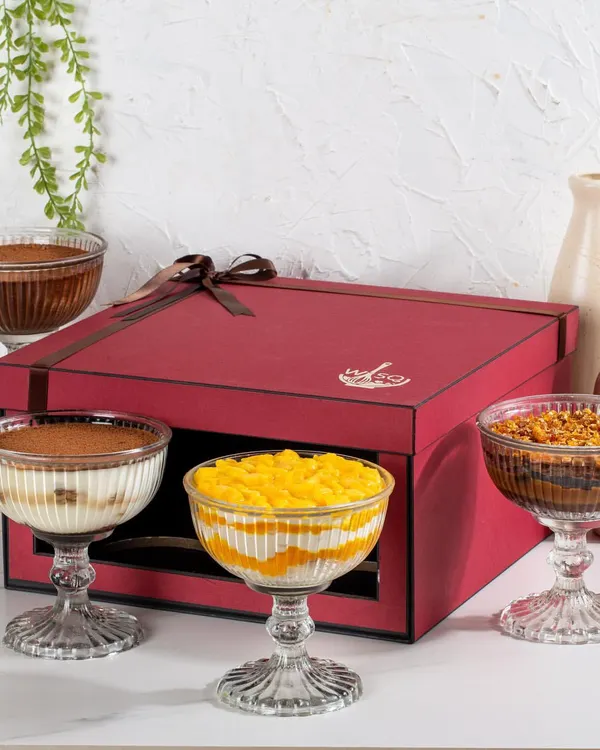 My four-dessert gift box is designed for sharing. It features a curated selection of my Classic Tiramisu, Dark Chocolate Mousse, Mango Cream Cheese Trifle, and Chocolate & Salted Caramel Trifle.