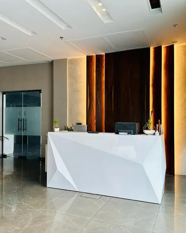 A wide view of the reception area I designed in Ambala, showcasing the geometric desk, back-lit wood paneling, and polished flooring that combine to create a modern and impressive entrance.