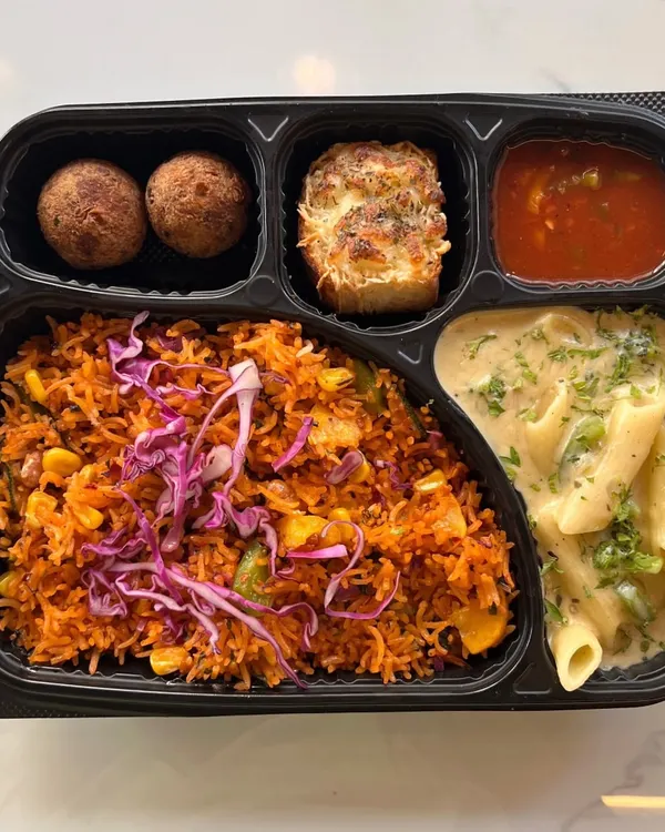 This meal box showcases our multi-cuisine capabilities, combining Continental and Oriental flavors. It includes creamy white sauce pasta, Mexican rice, cheese-topped garlic bread, and savory balls, offering a unique fusion experience.