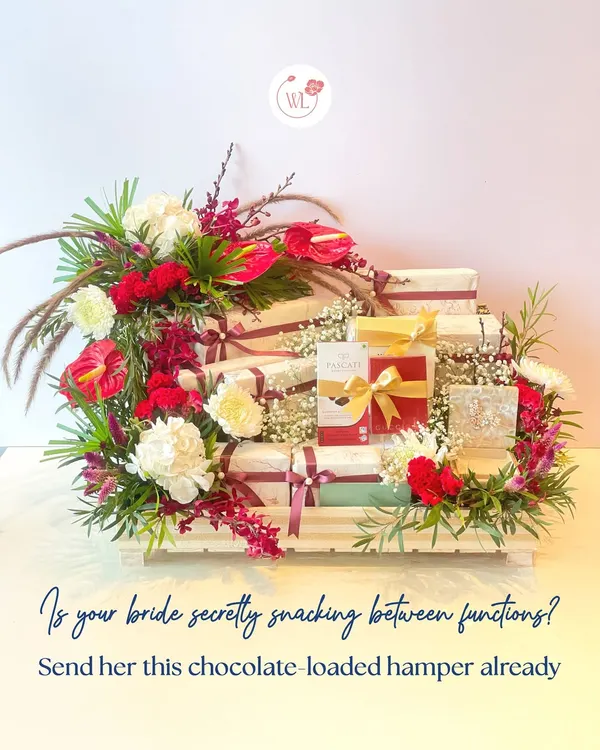 Is your bride secretly snacking between functions? Send her this chocolate-loaded hamper, beautifully arranged in a tiered wooden crate with red and white florals.