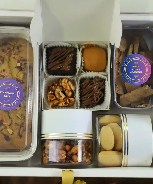This is what a box full of happiness looks like. My celebration hamper is packed with a variety of my best homemade, eggless treats, from a nutty Pistachio Loaf and gooey brownies to classic Nankhatai and savory Honey Chilli Peanuts.