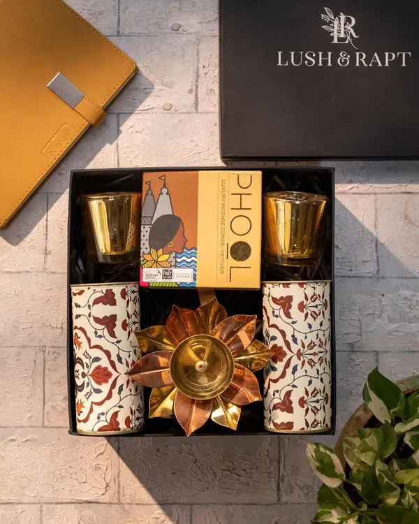 A classic Diwali hamper featuring Phool incense, patterned tumblers, and a brass lotus diya. This is a perfect example of a traditional yet elegant gift for clients and employees.