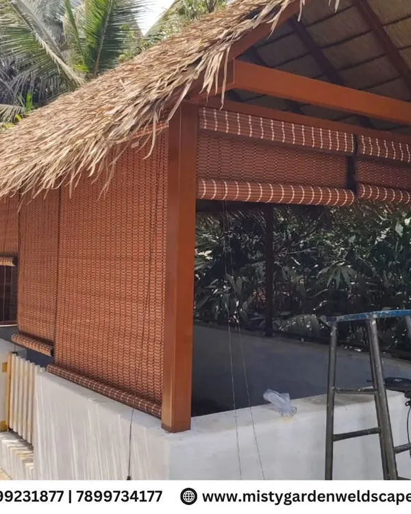 A completed premium cow shed with a traditional thatched roof and bamboo blinds for ventilation. This structure at Mother India Farming Pvt Ltd is designed to be both functional and aesthetically pleasing.