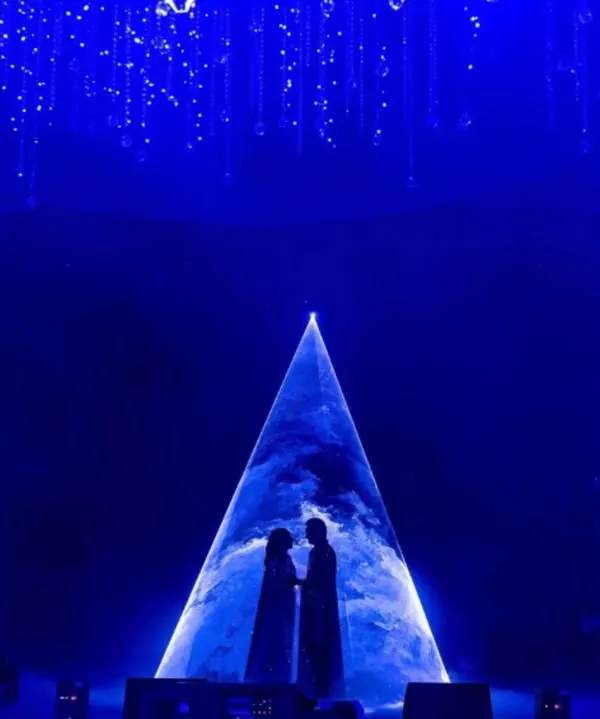 A couple's silhouette against a cosmic projection creates a moment of pure theatrical magic. This stage design for a Sangeet focuses on powerful lighting and visuals to tell a love story written in the stars.