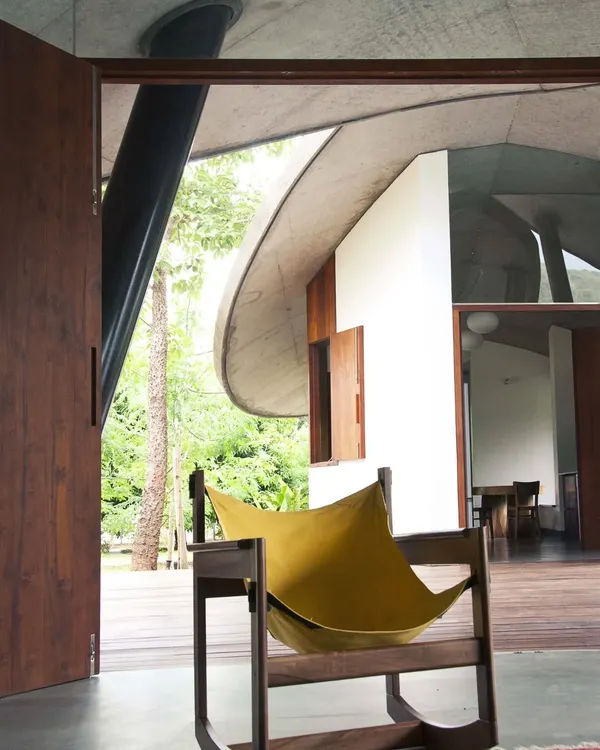 In 'The Leaf House', the living space opens completely to the wooden deck and surrounding trees. The curved concrete roof provides shelter while feeling as light and organic as a canopy of leaves.