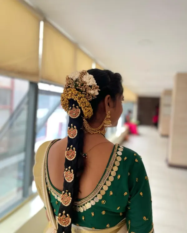 A stunning example of student work. This South Indian bridal hairstyle features a traditional long braid decorated with intricate temple-style jewelry, known as Jada Billalu, and a floral veni.
