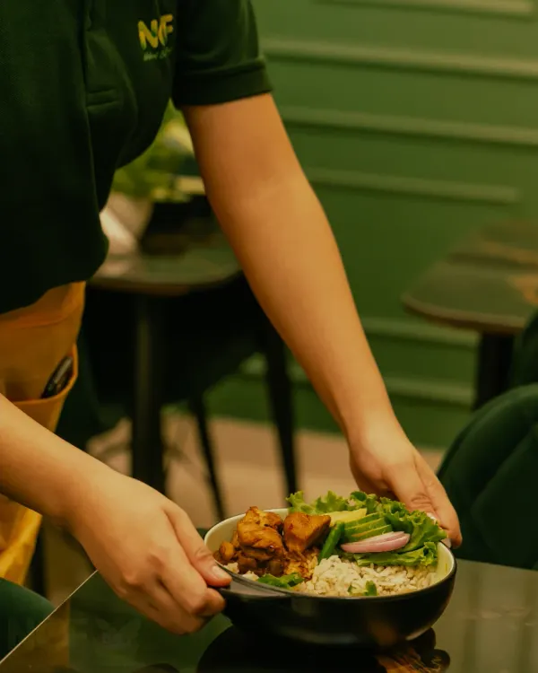 A staff member serving one of our popular 5-in-1 rice bowls, ready for you to enjoy.
