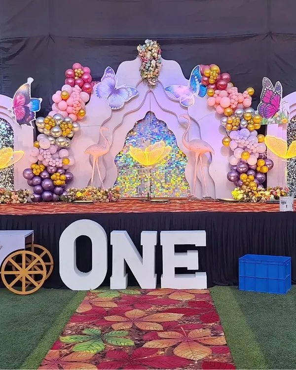 A grand first birthday setup with a butterfly theme. Notice the large 'ONE' marquee letters in the front, which are very popular for milestone birthdays.