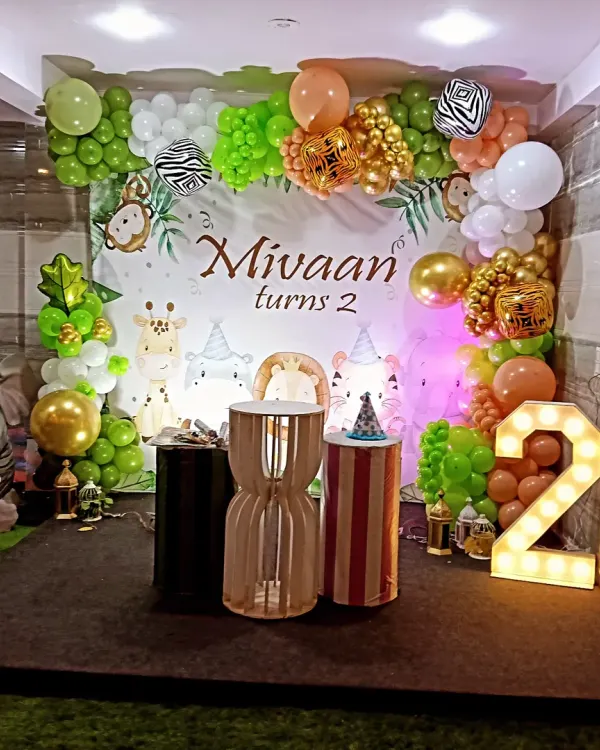 We brought a wild jungle safari to life for Mivaan's second birthday. This setup features a custom backdrop with adorable animal characters, a lush balloon arch in greens and golds, and a large light-up marquee number to mark the special age.