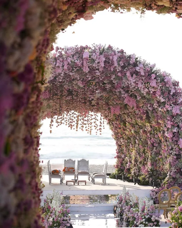 We believe in creating entrances that transport you. This colossal floral mandap, crafted from over one hundred thousand stems for a beach wedding, creates an ethereal tunnel of blossoms, perfectly framing the ocean view and the couple's sacred vows.