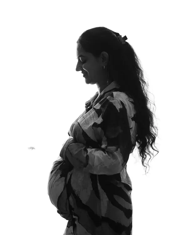 A beautiful high-key silhouette portrait. This black and white technique creates a striking and artistic image that emphasizes the profile and baby bump.
