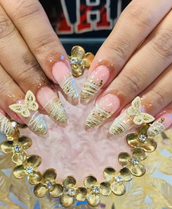 An intricate set of almond-shaped acrylic extensions featuring delicate gold thread work and stunning 3D butterfly charms. This is a perfect example of detailed, high-fashion nail art.