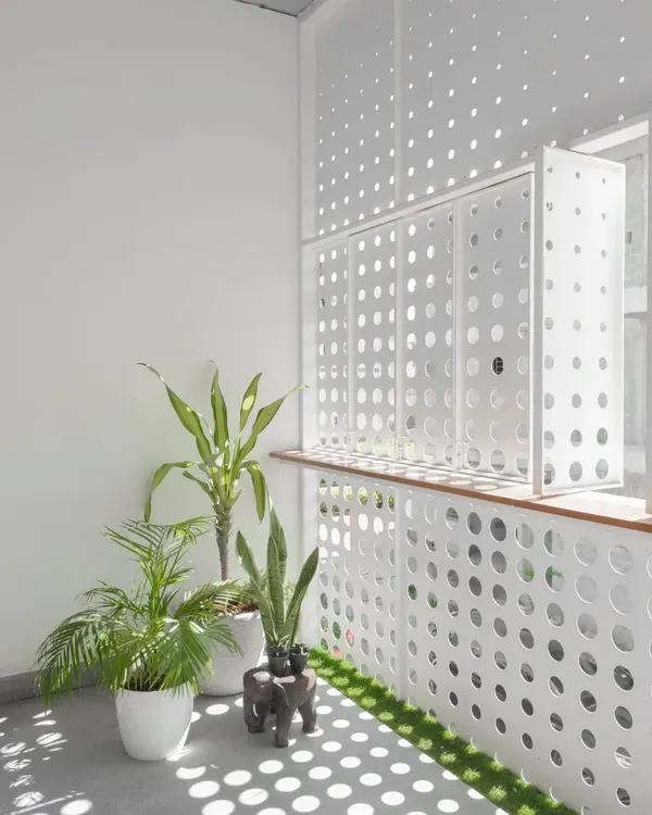 The front facade features an operable perforated metal screen. This dynamic element creates an ever-changing pattern of light and shadow within the home while ensuring privacy from the street.