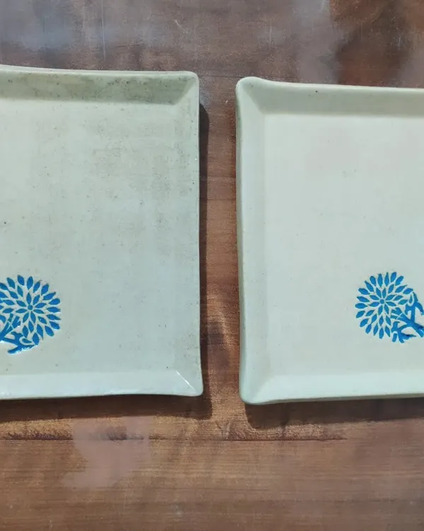 A pair of matching rectangular stoneware plates, perfect for serving appetizers or dessert. The simple, clean shape is decorated with a hand-stamped blue floral design, adding a pop of color to your table.