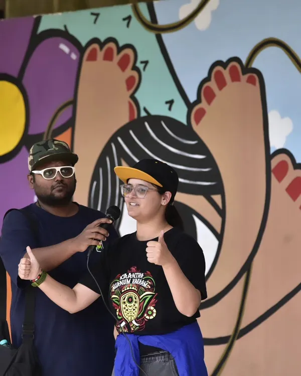 The power of sign language in action at Sign Fest 2024. An interpreter and a speaker share the stage, ensuring the message is accessible to everyone in our diverse audience. The vibrant mural behind them adds to the festive atmosphere.
