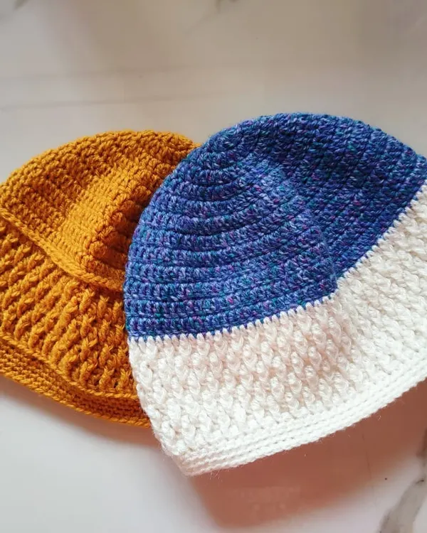 Two of my completed Sheldon beanies. This unisex hat pattern features a textured Alpine stitch panel and is shown here in mustard yellow and a blue and white combination.