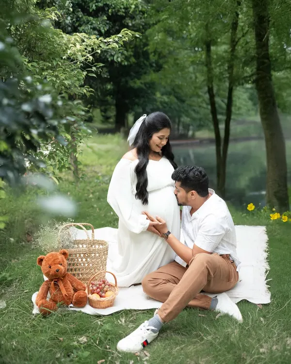 A romantic outdoor maternity session with a picnic setup by the water. This image captures the quiet anticipation and joy of expecting parents in a beautiful, natural setting.
