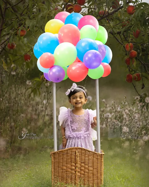 Up, up, and away! This hot air balloon prop creates a magical and whimsical scene for an outdoor birthday shoot, set against a beautiful green backdrop.