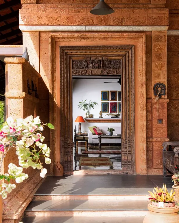 This intricately carved wooden doorway at the Varadarajan House in Coorg serves as a threshold between the outer world and a serene inner sanctuary. Framed by earthy laterite stone, it is an example of how we honor traditional craftsmanship, creating an entrance that feels both grand and deeply personal.