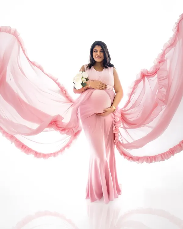 A beautiful solo portrait of a mother-to-be in a flowing pink maternity gown, creating a dynamic and angelic look against a clean white background. This style is perfect for celebrating the beauty of pregnancy.