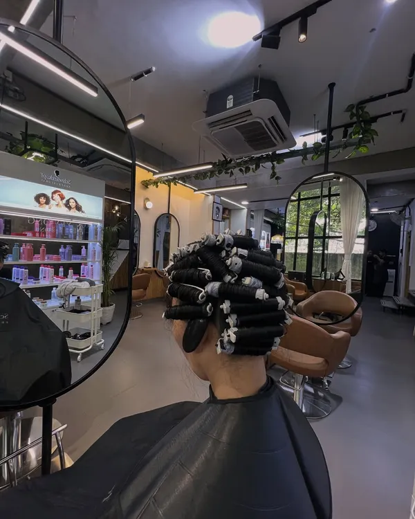 This is a behind the scenes look at the perming process. I carefully wrap sections of hair around perm rods, which is a crucial step to determine the size and shape of the final curls.