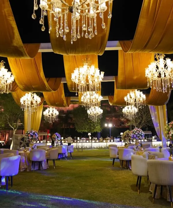 A sky full of stars and chandeliers. For this 'Golden Grandeur' reception, we created a breathtaking ceiling with flowing golden drapes and dozens of crystal chandeliers, making the outdoor space feel magical.