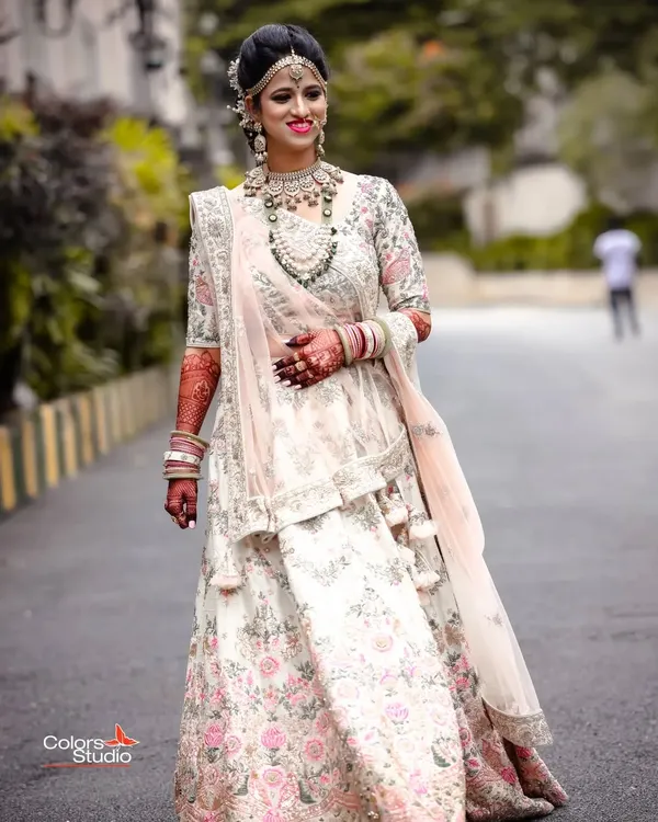 A full-length portrait of a stunning bride in her intricately embroidered floral lehenga, looking absolutely radiant on her wedding day.