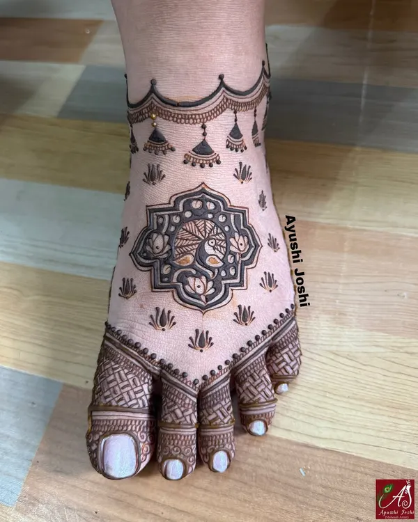 A minimal yet elegant bridal foot design. This mehendi features a central peacock motif with delicate hanging 'jhumkis' and simple patterns on the toes.