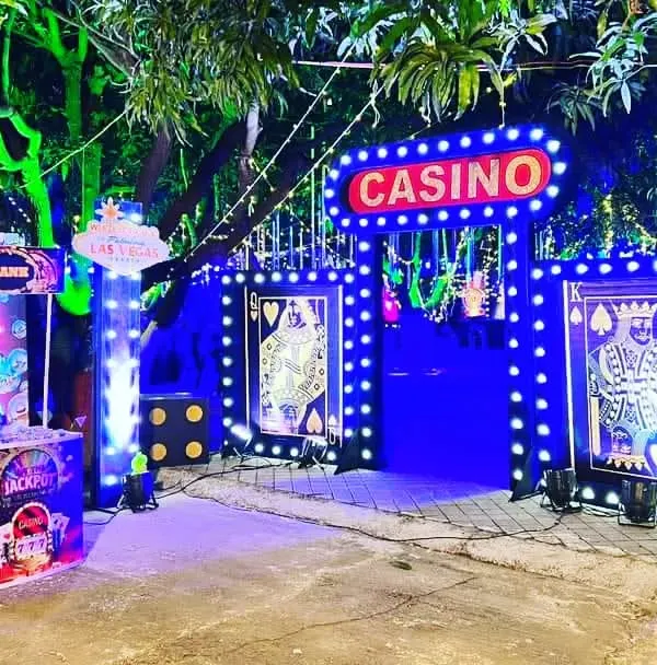 A grand entrance for a Casino Night themed party, featuring a lit-up 'Casino' sign, custom card-themed gates, and atmospheric blue lighting. This is how I set the stage for an unforgettable event right from the moment your guests arrive.