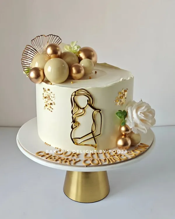 A sweet beginning. This elegant baby shower cake in white and gold is a beautiful way to celebrate a mom-to-be. The simple line art and cascading chocolate spheres create a modern and sophisticated look.