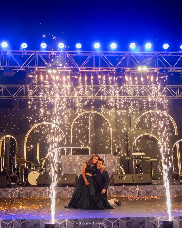 The couple takes the stage for their performance, framed by glowing arches and a shower of cold pyros. Our stage designs are built for these iconic, high-energy moments.