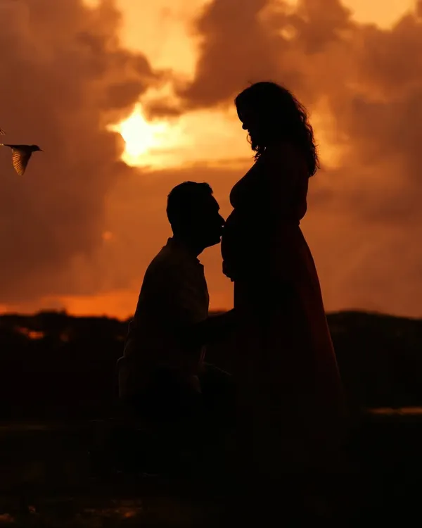 A breathtaking sunset silhouette of a couple, with a bird captured in flight. These outdoor sessions are timed perfectly to catch the golden hour, creating truly magical and artistic maternity portraits.