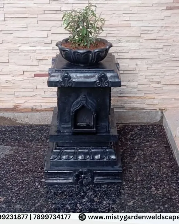 As part of a backyard makeover, we installed this traditional black stone Tulsi Katta, creating a sacred and beautiful focal point against a natural stone wall.