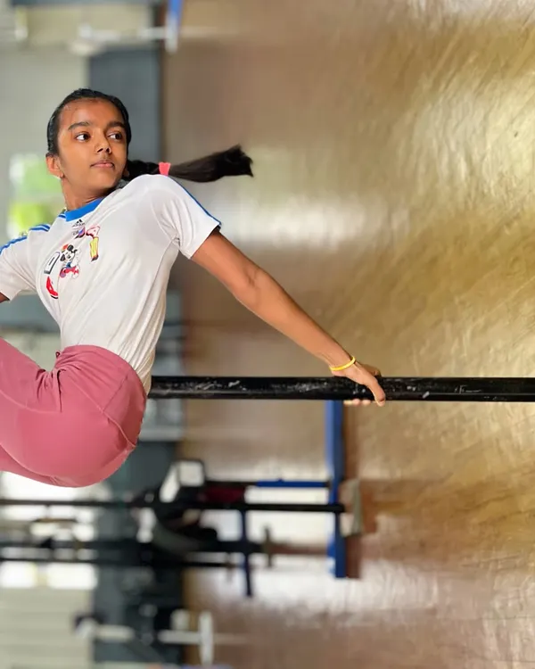 Strength, grace, and determination. This student holds a strong position on the bar, a fundamental piece of equipment for building the upper body and core strength needed for gymnastics.