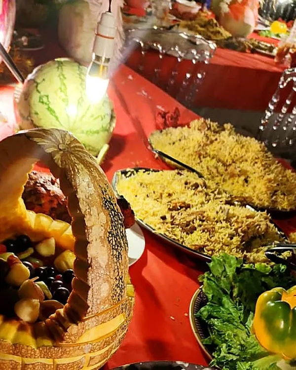 This is my special Mutton Biryani, a true bequest of paradise. You can see the long-grain rice, succulent pieces of mutton, and the beautiful presentation with fruit carvings. It's the star of any *shadikakhana*.