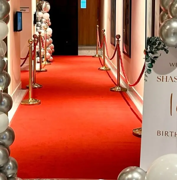 A glamorous entrance for an 18th birthday party. We rolled out the red carpet and lined it with velvet ropes and silver and white balloon columns to give guests a VIP welcome.