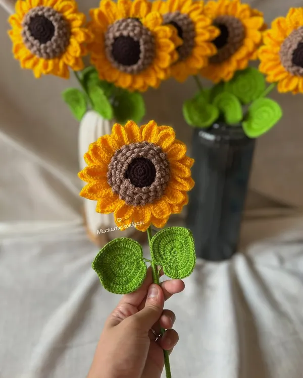 A single, handcrafted 3D crochet sunflower held in hand, showcasing its detailed petals and vibrant colors. These are perfect as a single stem or as part of a larger bouquet.