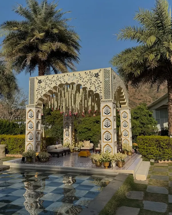 A wide view of our Rajasthani-inspired mandap, perfectly situated by a checkered pool and framed by palm trees at the Taj Aravali in Udaipur.