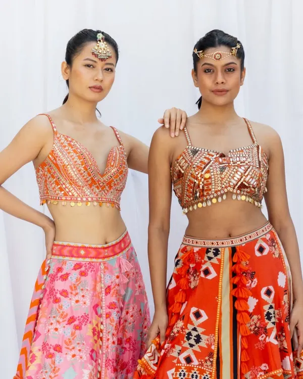A fashion-forward shot for a designer lookbook. This image focuses on the modern, embellished blouses and vibrant lehengas, perfect for a sangeet or cocktail event.