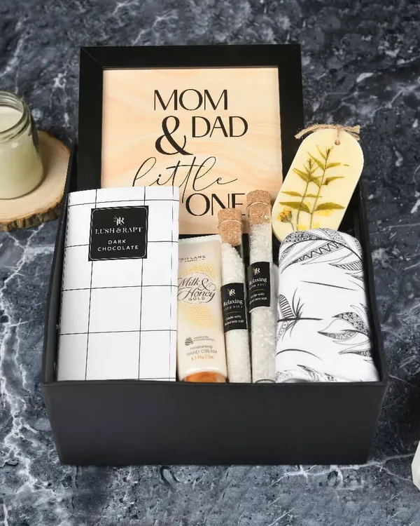 A special gift for the new family. My signature 'New Parents' hamper includes pampering products for mom and dad, a sweet wooden frame, and a little something for the baby.