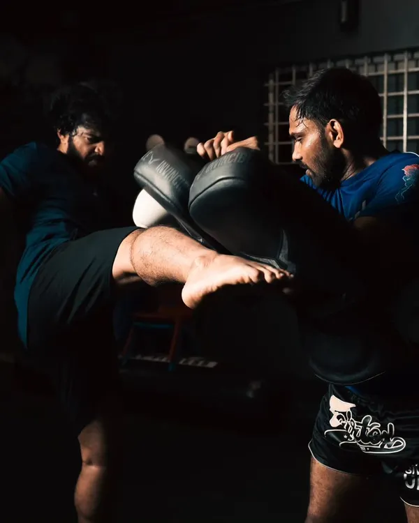 Power generated from the ground up. A student practices a roundhouse kick on the pads, focusing on hip rotation and impact.