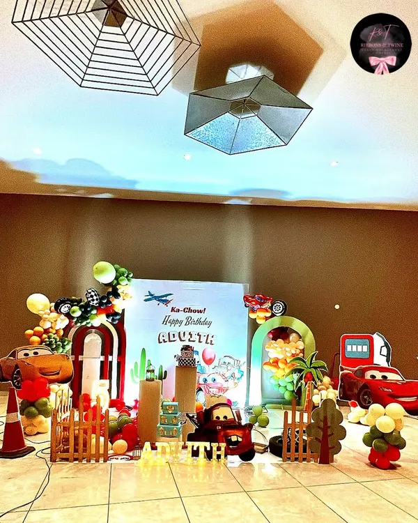 A full view of the Disney 'Cars' themed party for Advith. The setup includes a custom backdrop, multiple character cutouts, balloon arches, and themed props to create a complete Radiator Springs experience.