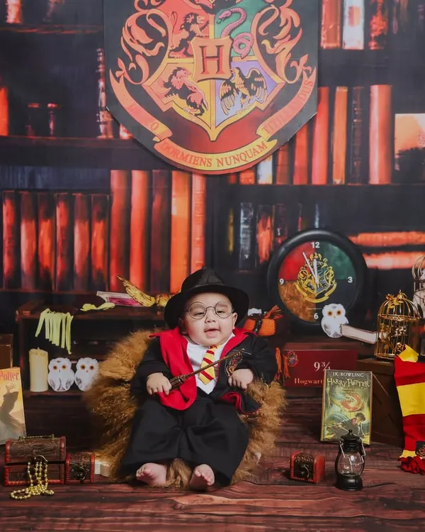Welcome to the wizarding world. This Harry Potter themed photoshoot features a custom-built library backdrop, Gryffindor colors, and magical props to bring a touch of Hogwarts to your baby's first portraits.