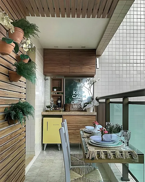 This compact balcony was transformed into a functional dining and bar area. The design includes a custom wooden cabinet with a mini-fridge, a wall-mounted bar, and a small dining table, proving that even small spaces can be highly functional.